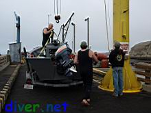 Eric Sedletzky prepares to attach the lift hook to the straps on his boat on the Arena Cove Pier.